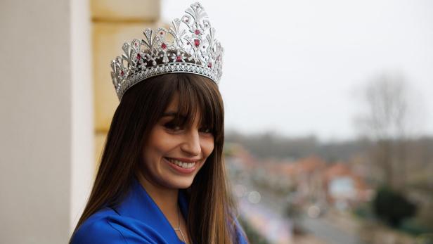 Eine junge Frau mit einer Krone lächelt in die Kamera.