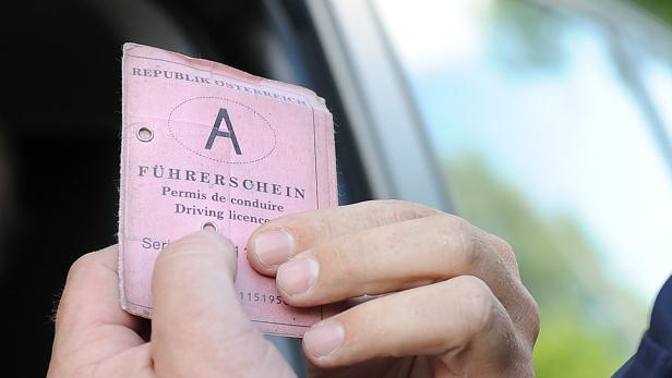Eine Hand hält einen alten, rosafarbenen Führerschein der Republik Österreich.