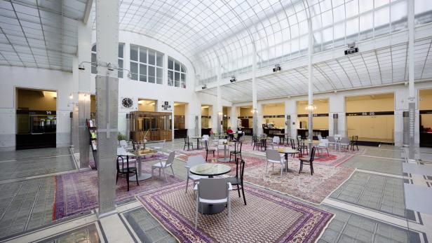Ein großer Raum mit Glasdach, Teppichen und Tischen mit Stühlen.