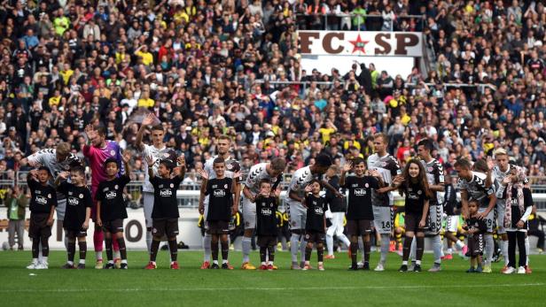 Fußballspieler des FC St. Pauli laufen mit Kindern ins Stadion ein.