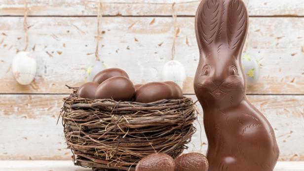 Chocolate Easter bunny, eggs and sweets on rustic background