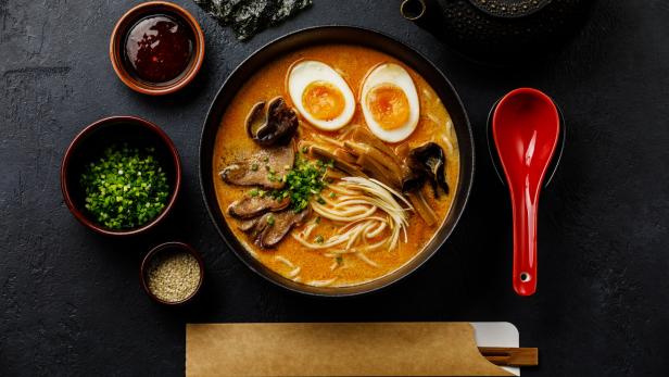 Ramen asian noodle in broth with Beef tongue meat, mushroom and Ajitama pickled egg in bowl on dark background