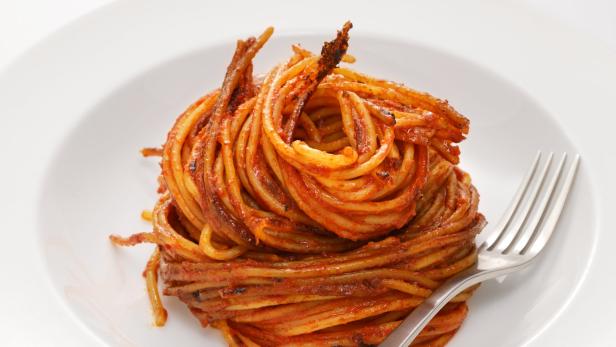 Ein Teller Spaghetti mit Tomatensauce und einer Gabel.