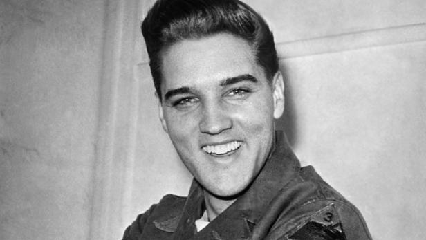 Elvis Presley in Uniform zeigt auf das Abzeichen seiner Einheit.