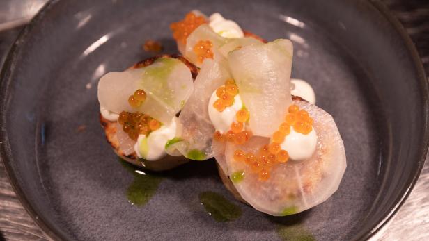 Drei Canapés mit Rettich, Creme und orangefarbenem Fischrogen auf einem Teller.