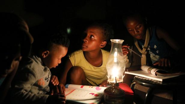 Kinder in der verarmten Township-Siedlung Soweto sind während eines Blackouts auf eine Öllampe angewiesen.