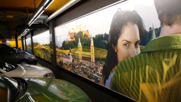 In einem Parkhaus hängt Werbung mit dem Gesicht einer Frau und der Stadt Salzburg.