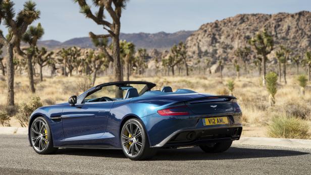 Ein blauer Aston Martin Vanquish steht in einer Wüstenlandschaft.