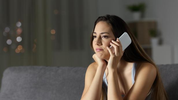 Eine gelangweilte Frau wartet während eines Telefongesprächs.