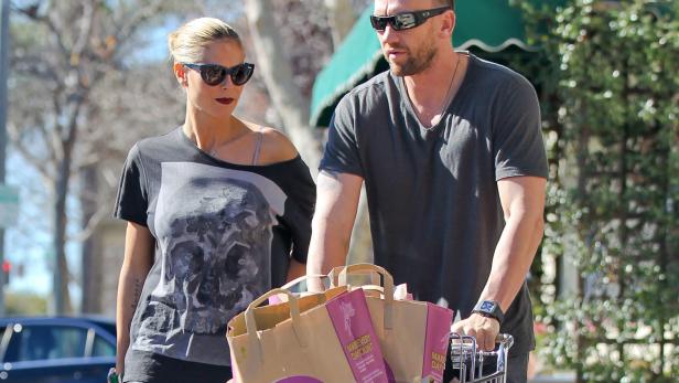 Heidi Klum und Tom Kaulitz schieben einen Einkaufswagen mit Papiertüten.
