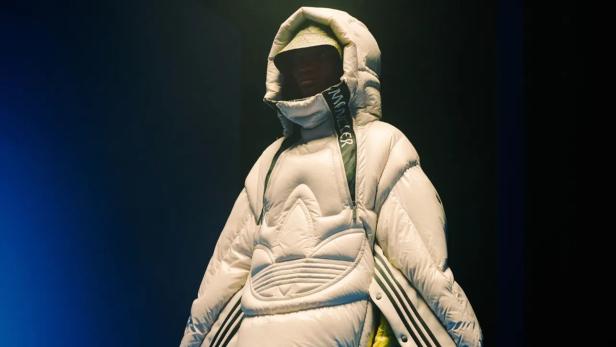 Eine Person trägt eine übergroße, weiße Daunenjacke von Moncler x Adidas.