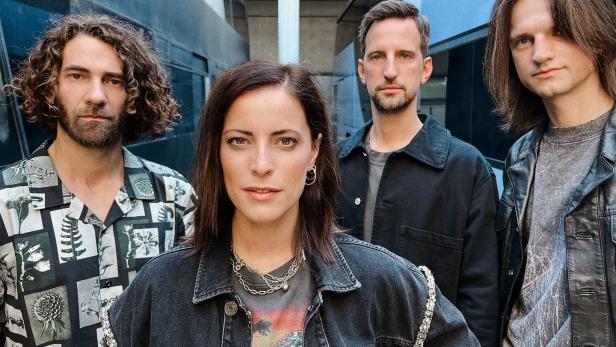 Eine Band posiert vor einem modernen Gebäude für ein Foto.