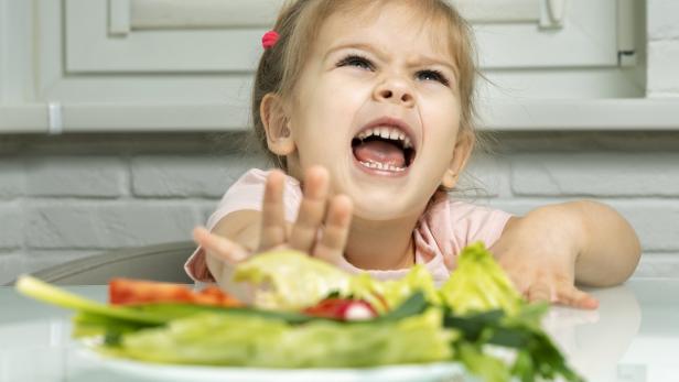 Ein kleines Mädchen weigert sich, Salat zu essen.