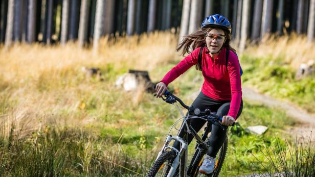 Ein Mädchen fährt mit einem Mountainbike durchs Gelände.