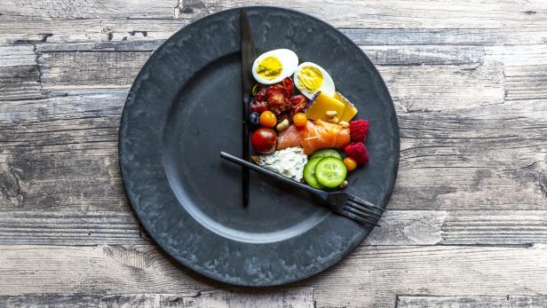 Variety of food on round plate, intermittent fasting - Stock-Fotografie