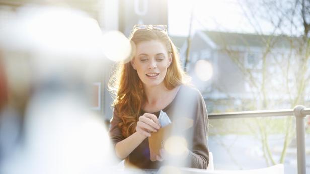 Eine junge Frau nimmt Geldscheine aus ihrem Portemonnaie.