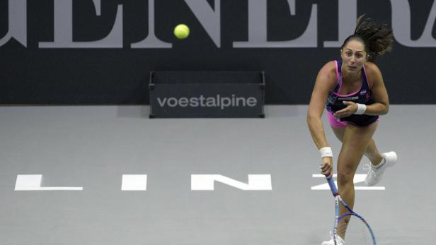 Eine Tennisspielerin beim Aufschlag auf einem Hallenplatz.