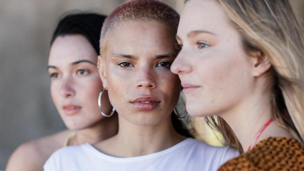 Drei junge, attraktive Frauen blicken in verschiedene Richtungen.