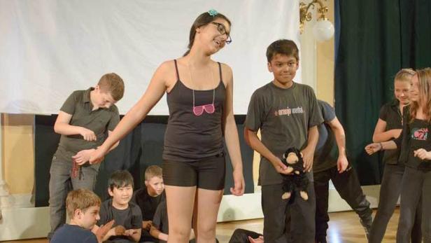 Eine Gruppe von Jugendlichen steht auf einer Bühne während einer Aufführung.