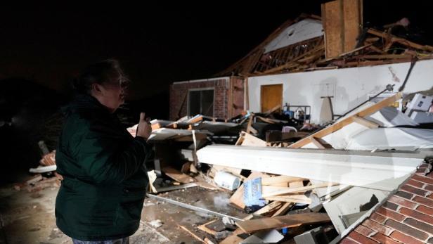 Nach einem Tornado in Norman, Oklahoma, steht eine Frau vor einem zerstörten Haus.