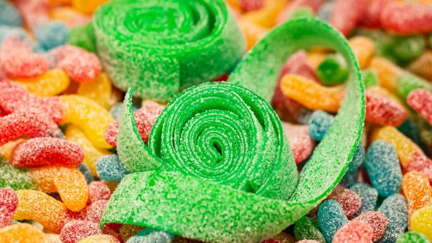 Nahaufnahme, Hintergrund mit grün gerollten Gummis, die mit Zucker überzogen sind. - Stock-Fotografie