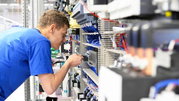 young apprentice worker in an industrial company assembling electronic components in the mechanical engineering of a modern factory