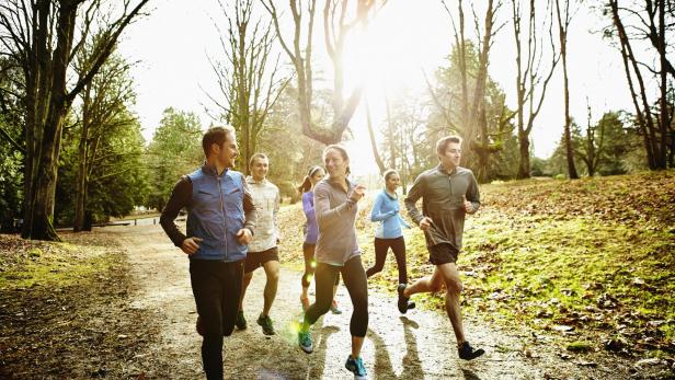 Smiling friends running together in park - Stock-Fotografie