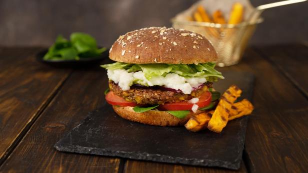 Köstliche frische hausgemachte vegane Linsen Burger auf einem rustikalen dunklen Hintergrund.