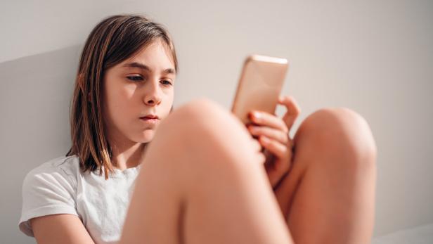Ein Mädchen schaut ins Smartphone.
