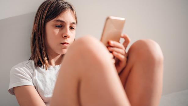 Ein Mädchen schaut ins Smartphone.