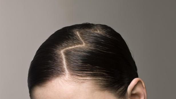 Frau mit freien Schultern und Zickzack-Scheitel im Haar.