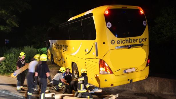 Ein gelber Reisebus der Marke „Eichberger“ steckt fest und wird von Feuerwehrleuten geborgen.