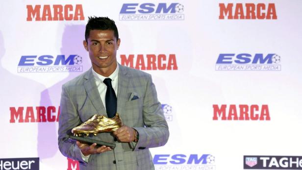 Cristiano Ronaldo im Anzug hält einen goldenen Schuh in der Hand.