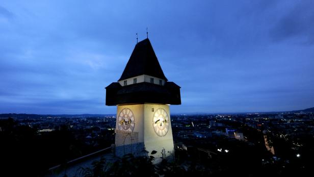 Der Grazer Uhrturm bei Dämmerung mit Blick auf die Stadt.