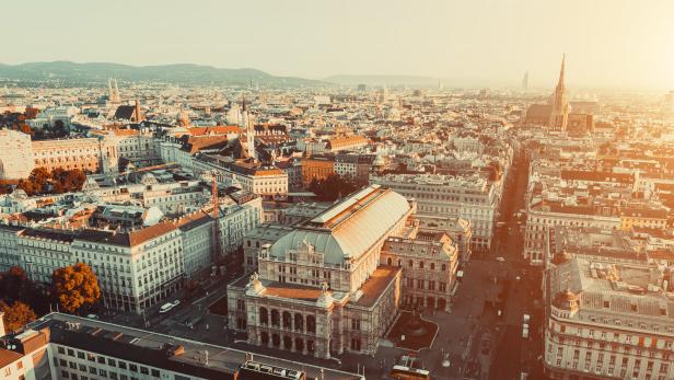 Luftaufnahme der Wiener Staatsoper und der umliegenden Stadtlandschaft bei Sonnenaufgang.