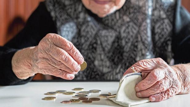 Elderly woman sitting at the table counting money in her wallet.