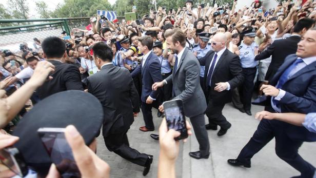 Fans push towards policemen as they take pictures and videos of former England soccer captain David Beckham upon his arrival at Tongji University, in Shanghai June 20, 2013. Beckham cancelled his event at Tongji University after a stampede accident happened upon his arrival injuring at least five people on Thursday, local media reported. REUTERS/Stringer (CHINA - Tags: DISASTER SPORT SOCCER) CHINA OUT. NO COMMERCIAL OR EDITORIAL SALES IN CHINA