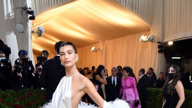 Hailey Bieber in einem weißen Kleid mit Federn auf dem roten Teppich.