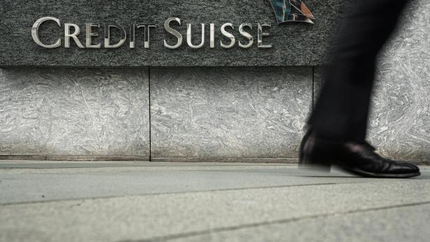 Pedestrian walks past a logo of Credit Suisse outside its office building in Hong Kong