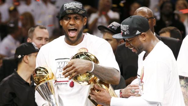 Miami Heat&#039;s LeBron James (L) holds the Bill Russell MVP Trophy and the Larry O&#039;Brien Trophy with teammate Dwyane Wade after their team defeated the San Antonio Spurs in Game 7 to win the NBA Finals basketball playoff in Miami, Florida June 20, 2013. REUTERS/Mike Segar (UNITED STATES - Tags: SPORT BASKETBALL)