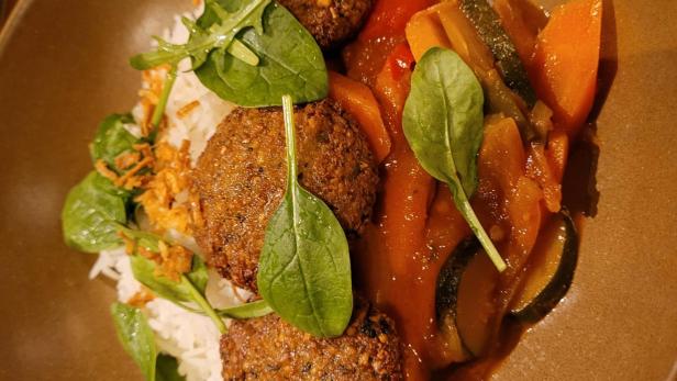 Eine Schüssel mit Falafel, Reis und geschmortem Gemüse wird serviert.