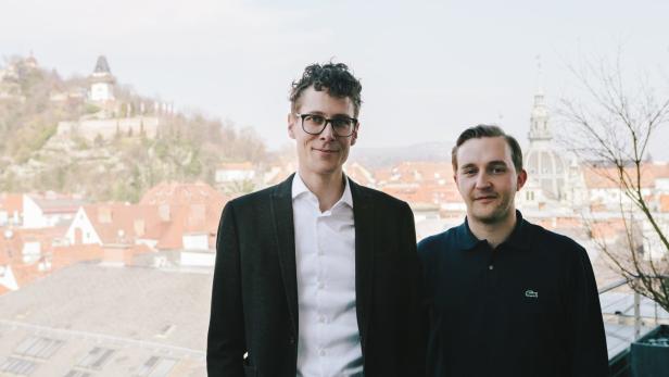Zwei Männer posieren vor der Skyline von Graz, Österreich.