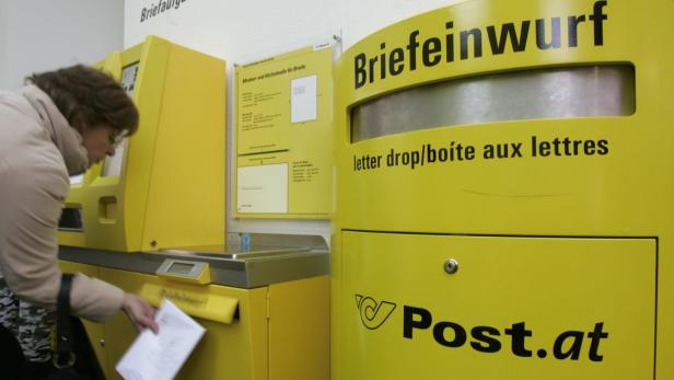 Eine Frau wirft einen Brief in einen gelben Briefkasten der Post.at.