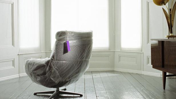Chair covered in bubble wrap by large bay window