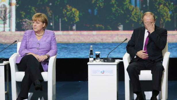 epa03754248 German Chancellor Angela Merkel (L) and Russian President Vladimir Putin (R) attend the plenary session of the St. Petersburg International Economic Forum (SPIEF) in St. Petersburg, Russia, 21 June 2013. The German chancellor&#039;s visit to the conference was marred by her last minute cancellation of a planned exhibit opening at the St. Petersburg Ermitage Museum because of a disagreement with Russian officials over who should give introductory remarks, sources in the German delegation told media. EPA/ANATOLY MALTSEV