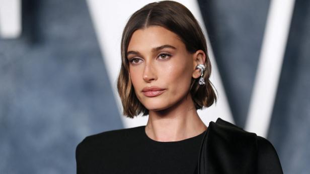 Hailey Bieber mit kurzem, gewelltem Haar und einem auffälligen Ohrring.