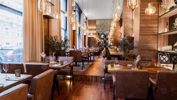 Ein elegantes Restaurant mit Holzböden, braunen Ledersesseln und dekorativen Lampen.