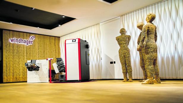 Ein Ausstellungsraum mit Windhager Heiztechnik und drei Holzstatuen.