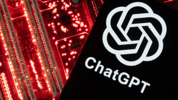 Das ChatGPT-Logo auf einem Smartphone, das vor einer rot beleuchteten Computerplatine liegt.