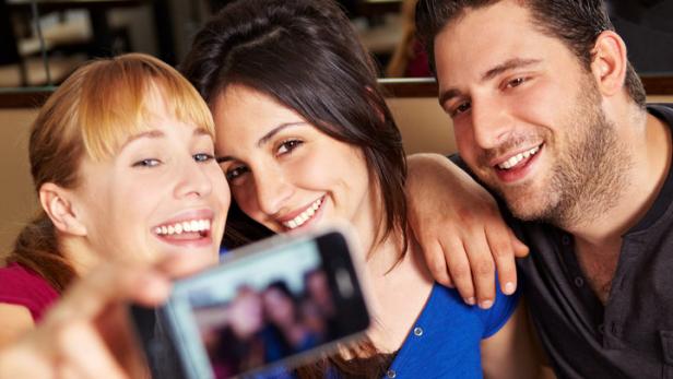 Drei Freunde machen ein Selfie in einem Café.